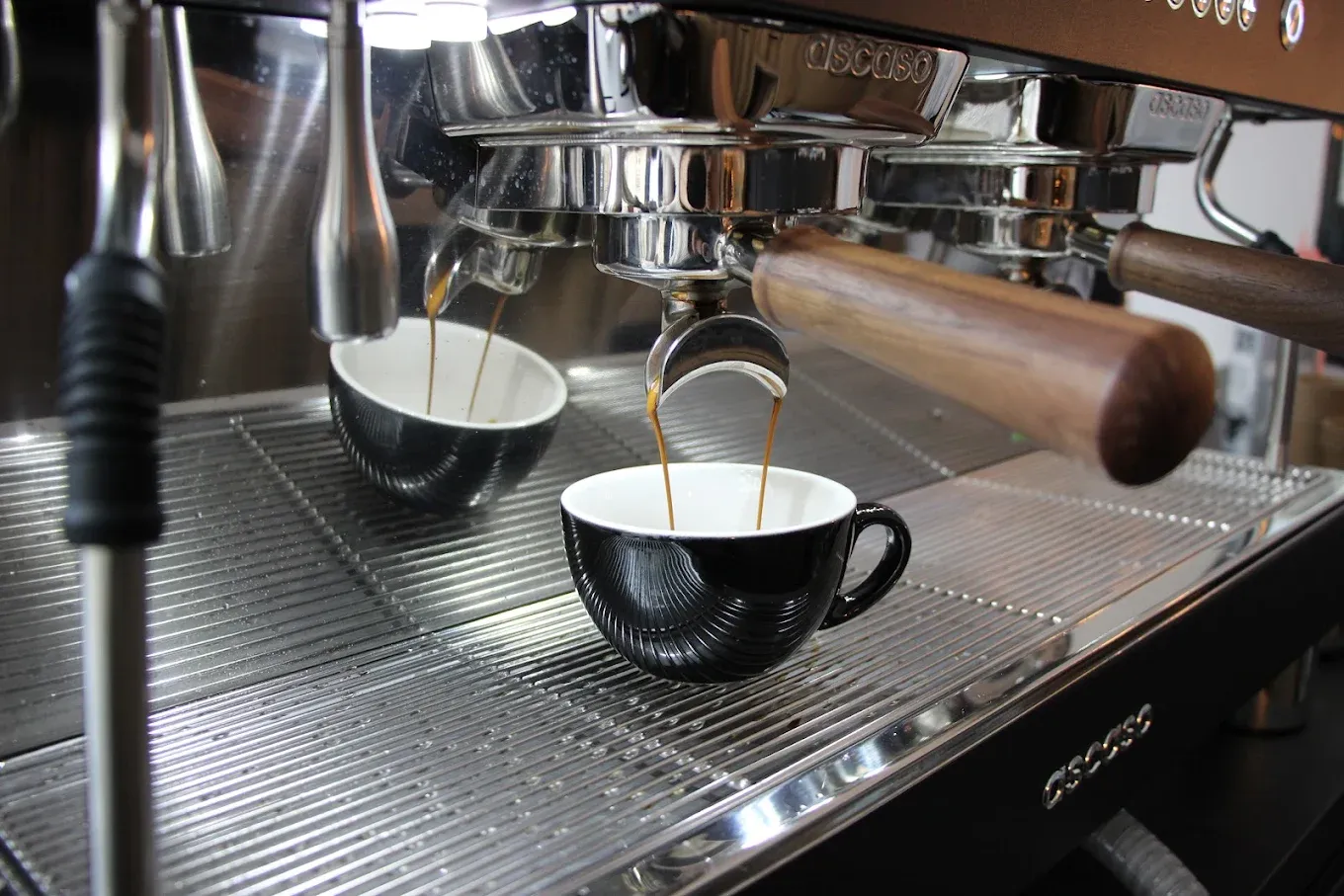 Espresso läuft aus der Siebträgermaschine in eine schwarze Tasse